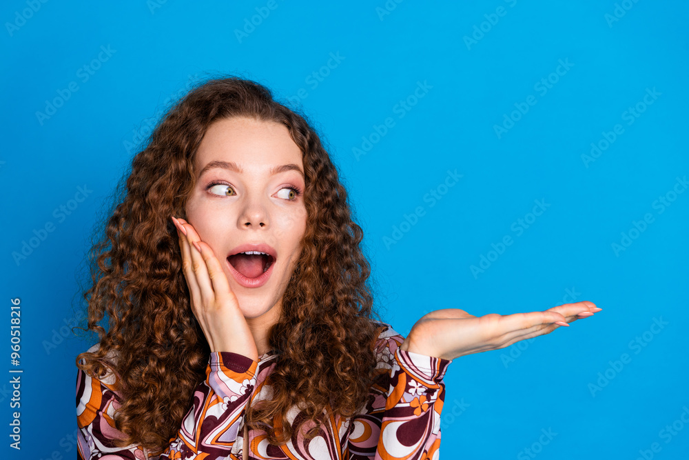Photo portrait of attractive young woman hold look shocked empty space dressed stylish colorful clothes isolated on blue color background Photo portrait of attractive young woman hold look shocked empty space dressed stylish colorful clothes isolated on blue color background