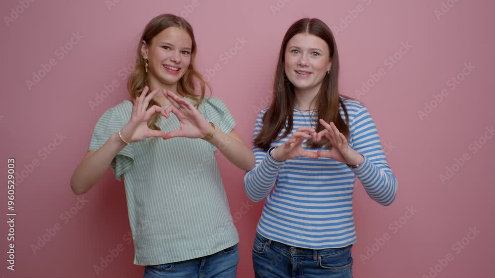 Heart Pose By Two Teenage Girls Against Pink Backdrop Heart Pose By Two Teenage Girls Against Pink Backdrop