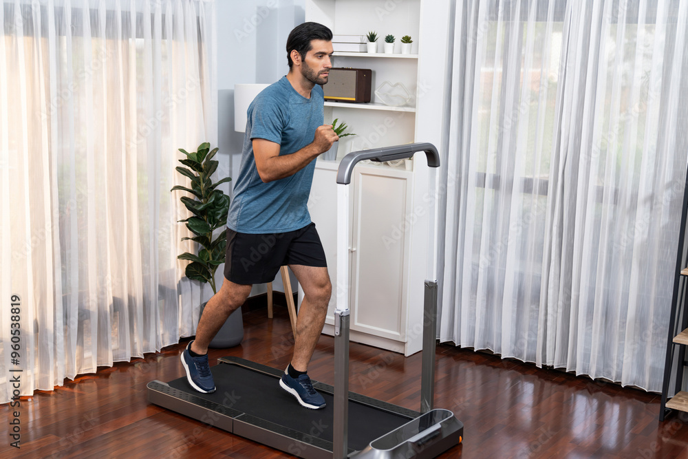 Fototapeta premium Athletic and sporty man running on running machine during home body workout exercise session for fit physique and healthy sport lifestyle at home. Gaiety home exercise workout training.