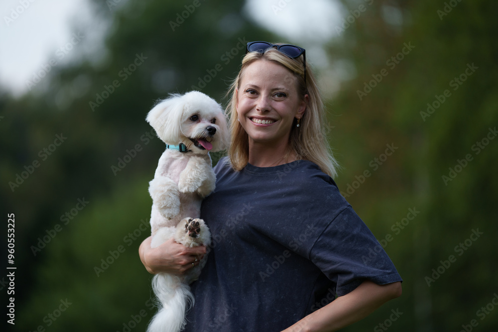 Portrait of smiling young woman kiss dog in Natural Park. Dog lover woman wearing blue dress with dog during good day. Concept of friendship and beautiful girl with a small dog Portrait of smiling young woman kiss dog in Natural Park. Dog lover woman wearing blue dress with dog during good day. Concept of friendship and beautiful girl with a small dog