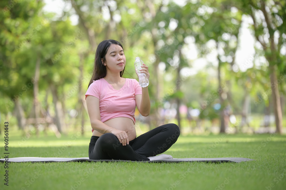 Asian healthy pregnant woman relaxing in the garden and holding water bottle Asian healthy pregnant woman relaxing in the garden and holding water bottle