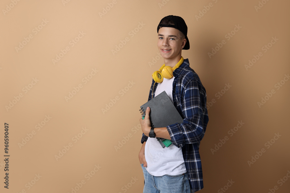 Portrait of smiling teenage boy with books on dark beige background. Space for text Portrait of smiling teenage boy with books on dark beige background. Space for text
