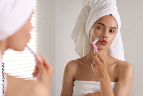 Bilde på lerret Beautiful woman shaving face near mirror indoors