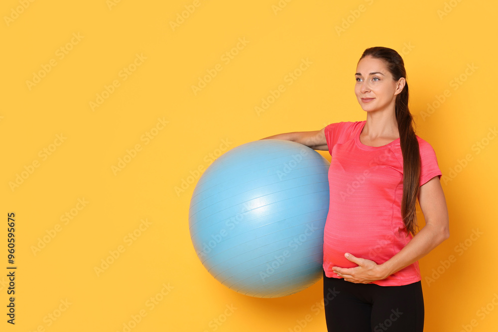 Beautiful pregnant woman with fitball on yellow background, space for text Beautiful pregnant woman with fitball on yellow background, space for text
