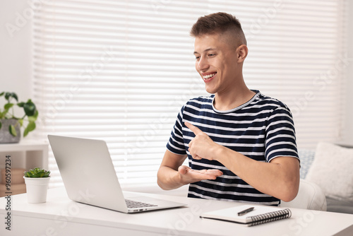 Young man using sign language during video call indoors