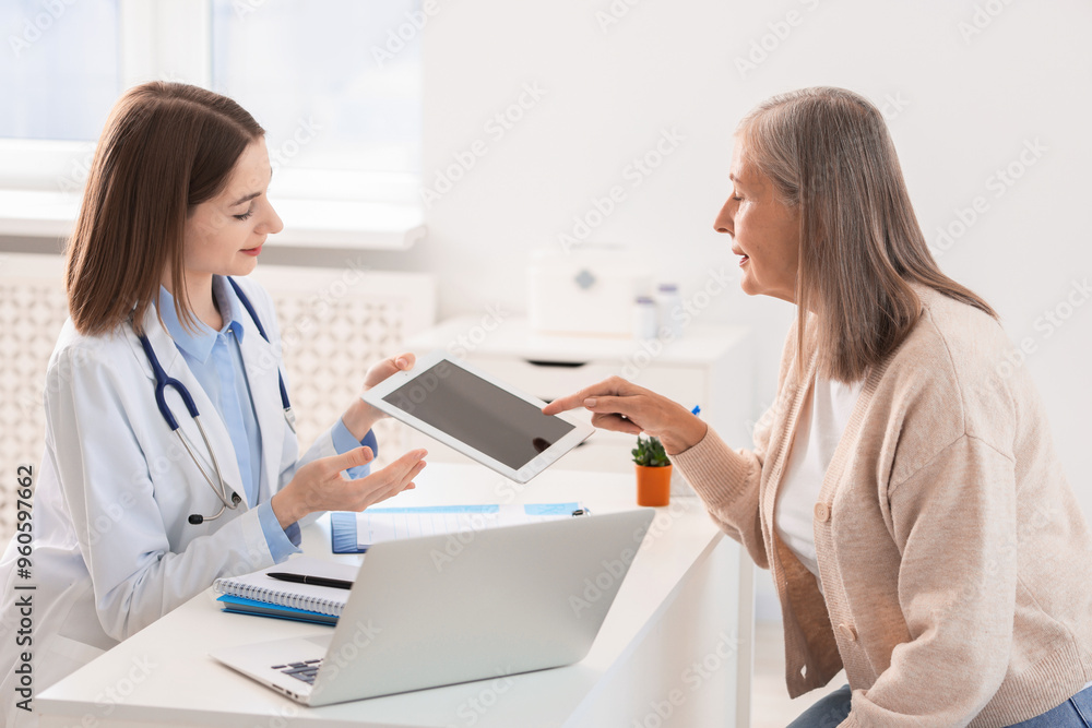 Healthcare worker and senior patient checking analysis results on tablet in hospital Healthcare worker and senior patient checking analysis results on tablet in hospital