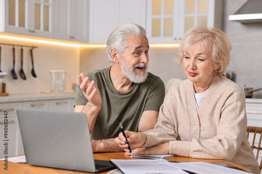 Pension savings. Senior couple planning budget at wooden table indoors Pension savings. Senior couple planning budget at wooden table indoors
