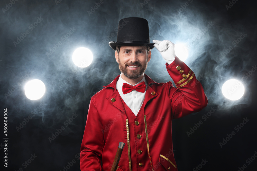 Φωτογραφία Portrait of showman in red costume, cane and hat on black background with spotli