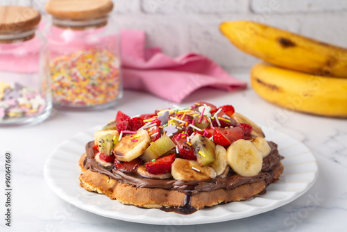 Obraz na płótnie Fruit waffles, bananas with chocolate sauce, strawberries, chocolate chips, handmade Turkish waffles with pistachio w salonie