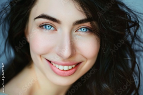 A radiant smile brightens the day of a young woman with dark hair and striking blue eyes during a sunny afternoon