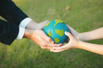 Businessman hand giving Earth globe to little boy as Earth day concept as corporate social responsible to contribute greener environmental protection for sustainable future generation. Gyre