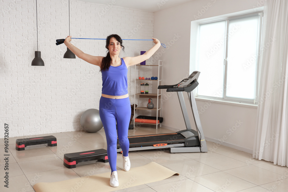 Fototapeta premium Sporty young woman with jumping rope training in gym