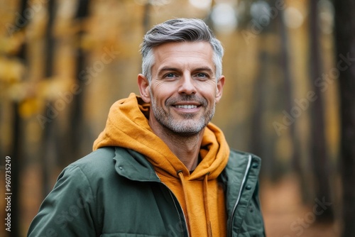 A smiling senior man stands in an autumn park in this portrait.