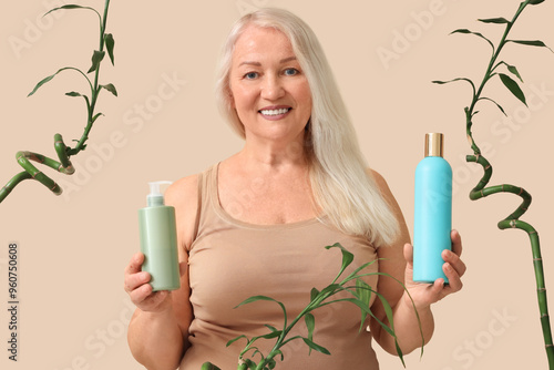 Mature blonde woman with hair care products and bamboo stems on beige background photo