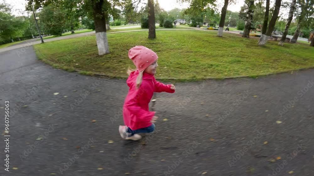 Young girl joyfully runs through a park, wearing a pink raincoat and matching hat. Her laughter and playful spirit embody the carefree essence of childhood in a vibrant outdoor setting Young girl joyfully runs through a park, wearing a pink raincoat and matching hat. Her laughter and playful spirit embody the carefree essence of childhood in a vibrant outdoor setting