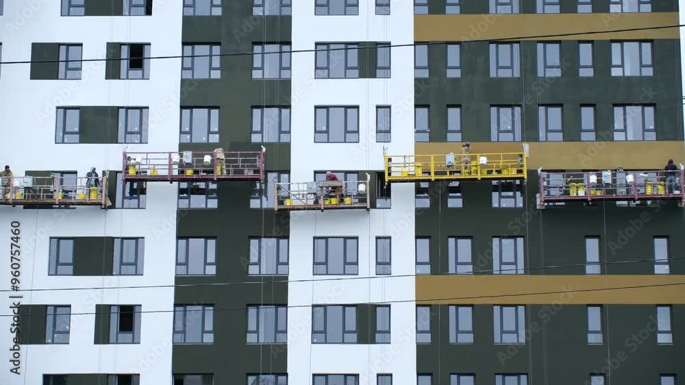 Workers securely stands on high lift near high-rise building. Employees add final touches to ultra-modern facade of newly constructed high-rise Workers securely stands on high lift near high-rise building. Employees add final touches to ultra-modern facade of newly constructed high-rise