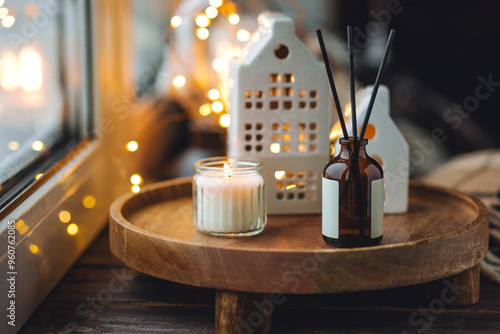 Idea how to create cozy holiday atmosphere and Christmas mood at home. Aromatherapy, aroma reed diffuser with sweet scent of cinnamon, anise, vanilla, faire lights, cute ceramic chandelier houses photo