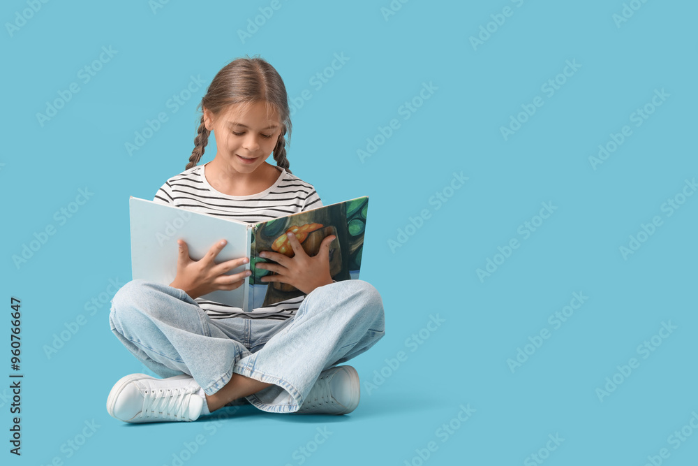 Cute schoolgirl reading book and sitting on blue background Cute schoolgirl reading book and sitting on blue background