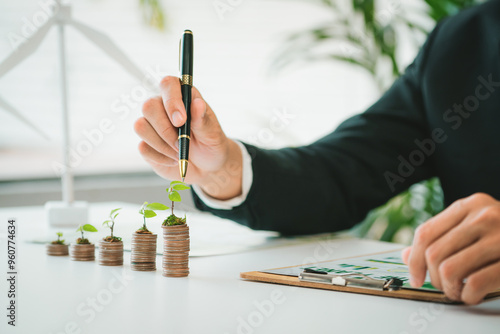 Fotografie Businessman with coin stack at his office as sustainable money growth investment or eco-subsidize