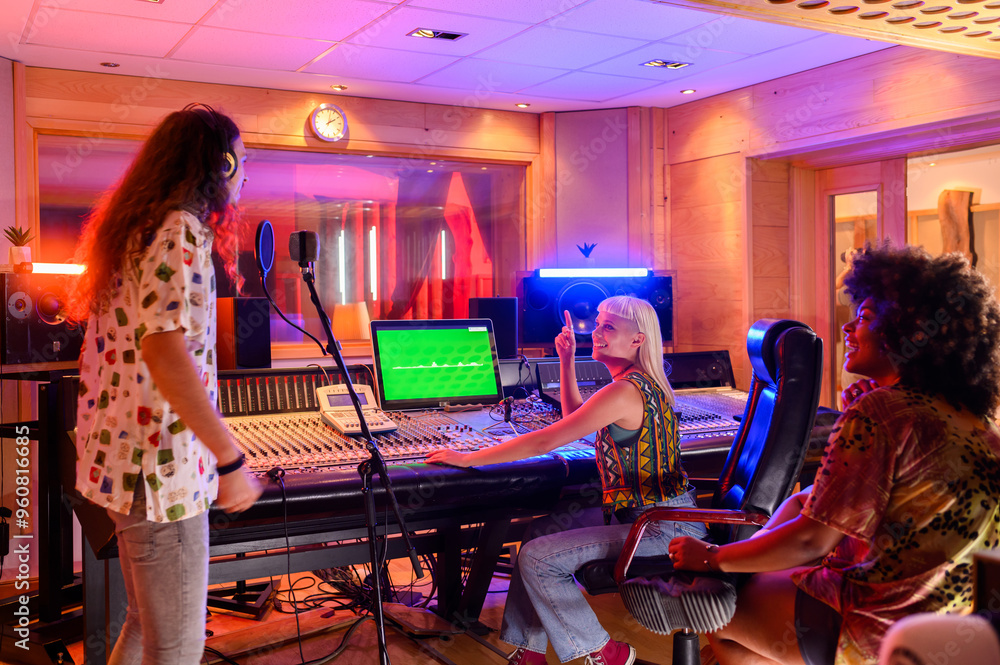 Singer singing a song while the producer is working on a soundboard in a studio
