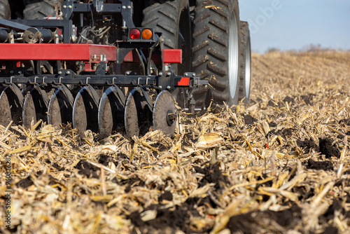 Tractor pulling chisel plow implement in farm field. Farm tillage, erosion control, and soil compaction concept. photo