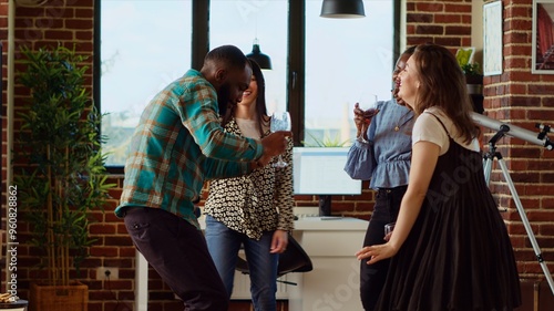 Fotografie Diverse group of school colleagues organizing apartment party, enthusiastically dancing to electronic songs
