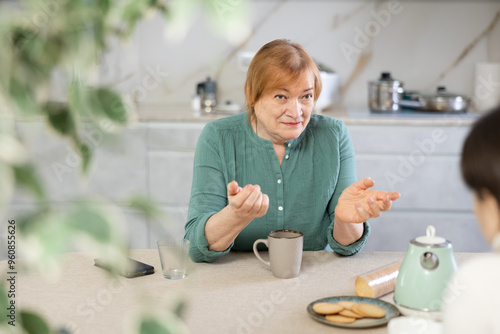 aged lady at home with cup of tea or coffee is talking about difficult life situation with friend. Problematic relationship concept photo