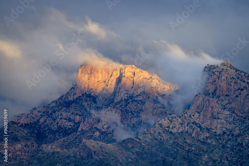 Sunlight illuminates Table Mountain in Pusch Ridge as misty storm clouds begin to clear. Tucson/Oro Valley, Arizona.