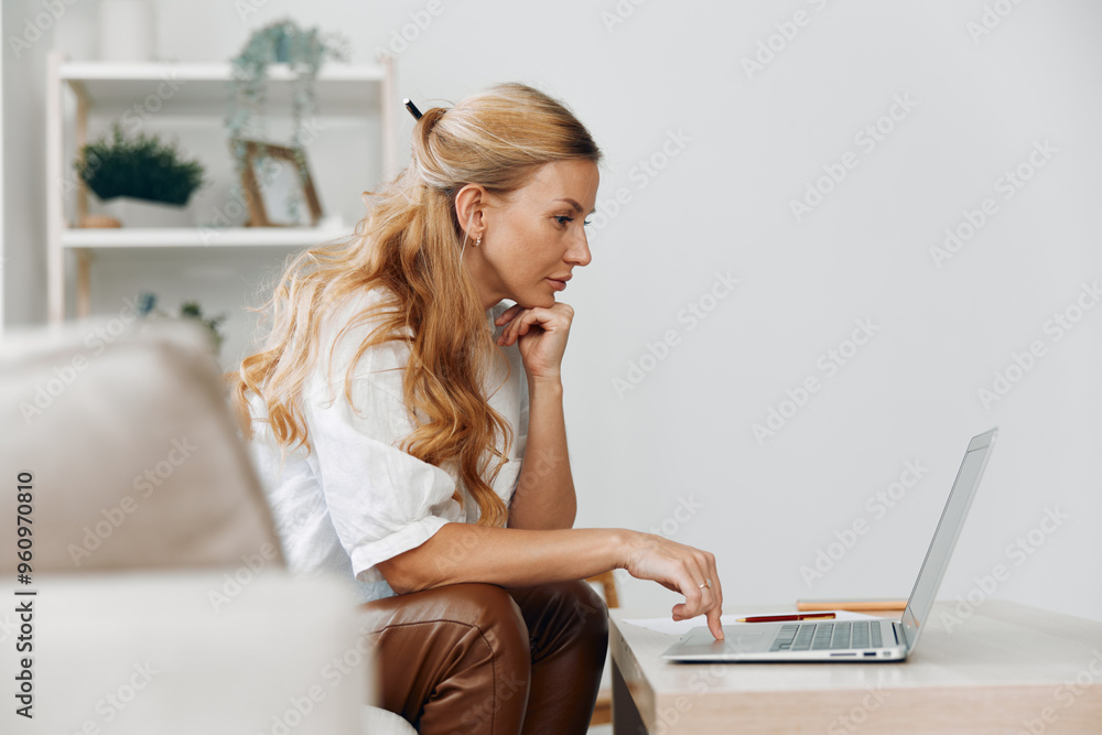 Woman on couch using laptop computer in modern living room with minimalist decor