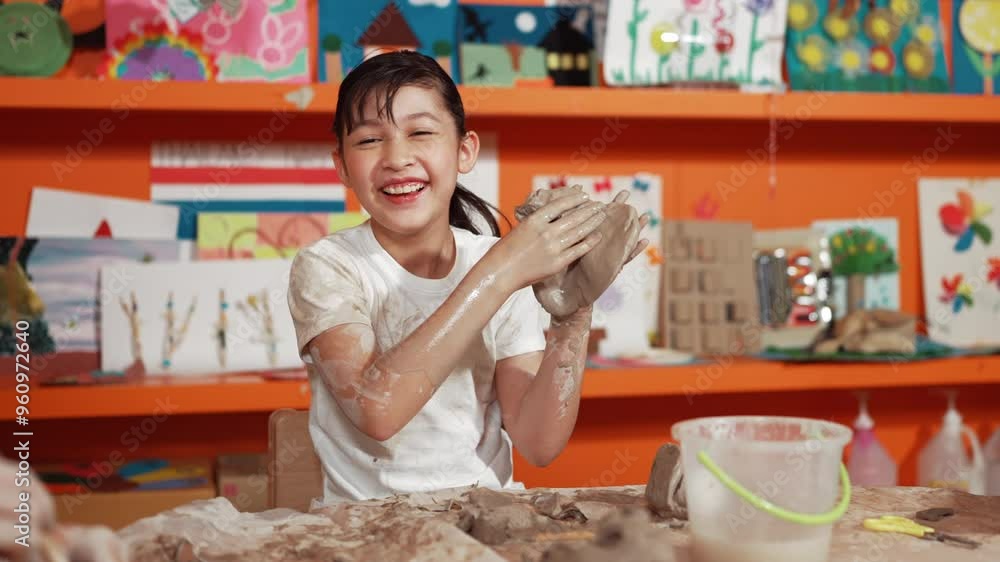 Asian high school student modeling clay on table with mud and bottle of water at pottery workshop. Group of happy diverse children working or making cup of clay. Creative activity concept. Edification Asian high school student modeling clay on table with mud and bottle of water at pottery workshop. Group of happy diverse children working or making cup of clay. Creative activity concept. Edification