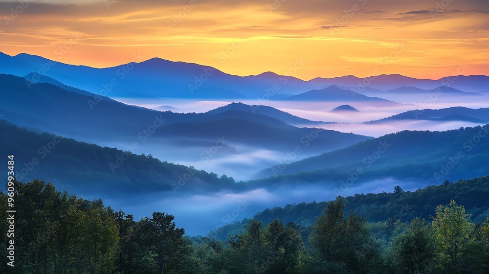 Obraz premium Majestic mountain range with morning mist and a vibrant sunrise.