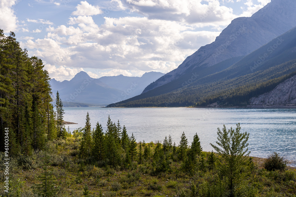 Scenic Mountain Lake View in Kananaskis, Alberta with Majestic Rocky Mountains and Blue Sky Scenic Mountain Lake View in Kananaskis, Alberta with Majestic Rocky Mountains and Blue Sky