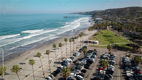 Aerial view of the Pacific Ocean waves crashing along the shore in La Jolla San Diego on a sunny day with views of the park, cliffs, palm trees, and sandy beaches in California photo