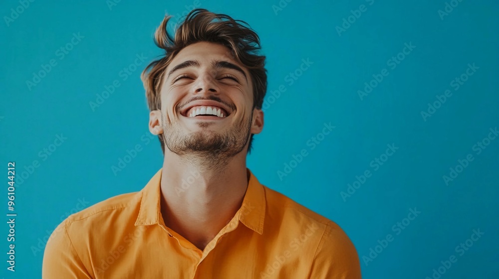 Portrait of a happy handsome man in a orange shirt, laughing against a blue background with copy space Portrait of a happy handsome man in a orange shirt, laughing against a blue background with copy space