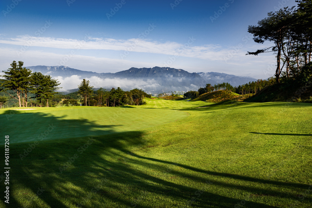 Obraz premium 구름이 산중턱에 걸려있는 풍경이 보이는 산위의 골프장.