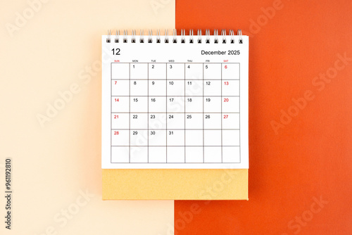 Directly above view of December 2025 desk calendar on orange background.