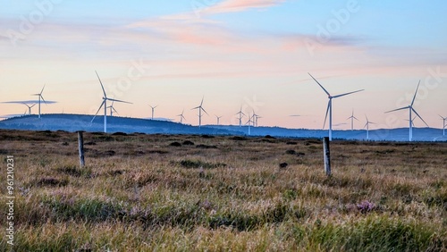 Obraz na płótnie Wind turbines on wind farm under beautiful orange sunset sky at Galway, Ireland, green energy, environment, nature background w salonie