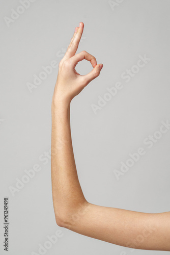 A Hand Forming an Okay Sign Against a Grey Background