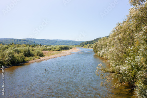 A winding river with a rocky shore and lush vegetation in the mountains