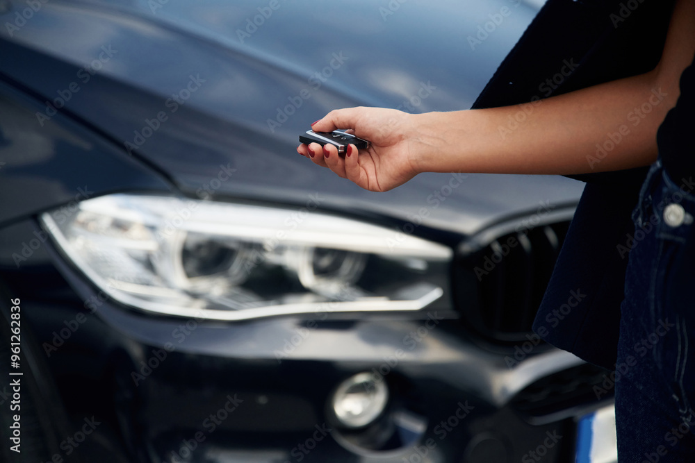 Focused close up view of woman hand that is holding key in front of the car Focused close up view of woman hand that is holding key in front of the car