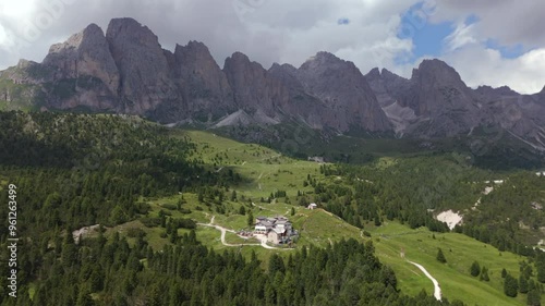 Breathtaking aerial view of Regensburger Hütte nestled in the green valleys of Seceda, surrounded by towering peaks and lush forests in the Dolomites. photo