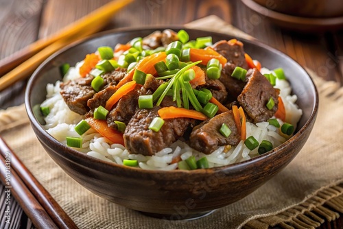 Asian rice bowl with beef, carrots, and green onions extreme close-up