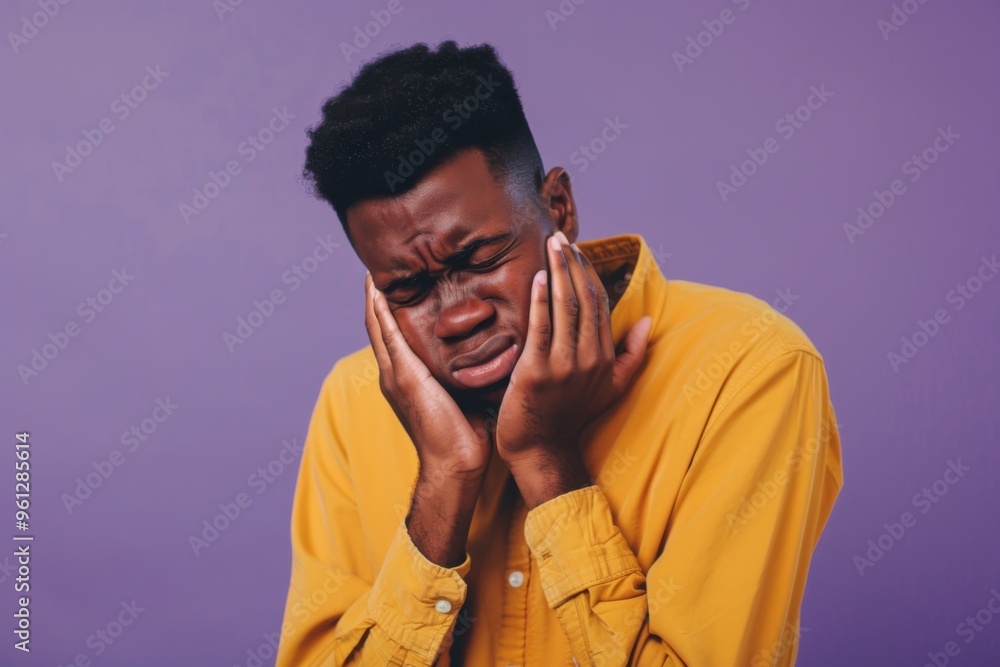 An emotional portrait of an unhappy African American man expressing sorrow against a vibrant purple background An emotional portrait of an unhappy African American man expressing sorrow against a vibrant purple background