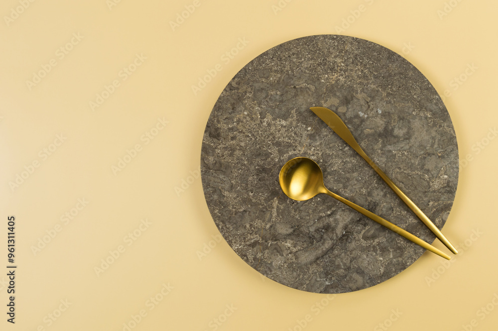 Top view of brown marble plate, gold cutlery on yellow background. Food presentation, stone tray. Copy space, flat lay. Top view of brown marble plate, gold cutlery on yellow background. Food presentation, stone tray. Copy space, flat lay.
