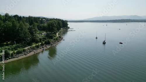 Shore of Serene lake in Beskid mountains, surrounded by greenery during a summer day - aerial view 4K photo