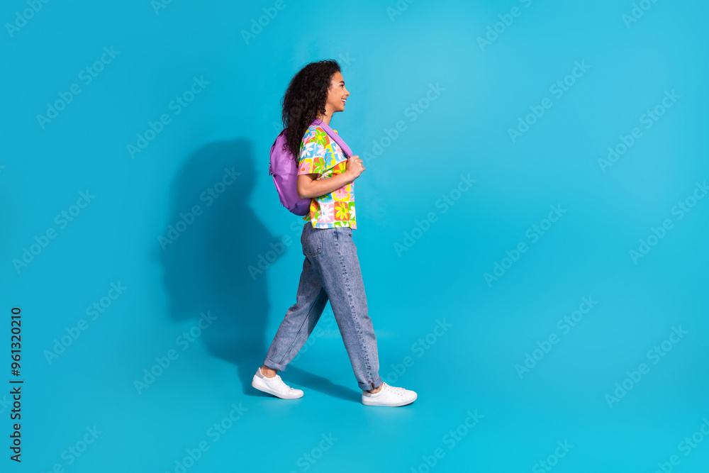 Full length photo of cute attractive lady dressed flower print t-shirt backpack walking empty space isolated blue color background Full length photo of cute attractive lady dressed flower print t-shirt backpack walking empty space isolated blue color background