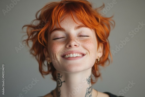 portrait of redhead bigender person with facial piercing laughing with closed eyes on grey backdrop, Generative AI photo