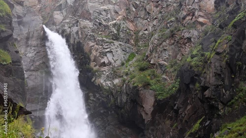 This stunning waterfall in a remote mountain area is surrounded by lush greenery and towering rocks, creating a refreshing atmosphere perfect for relaxation and reflection. photo