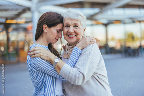 Elderly Woman and Young Adult Embrace Outdoors Smiling