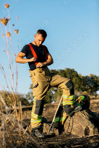 Firefighter Preparing Gear in a Burnt Forest Landscape photo